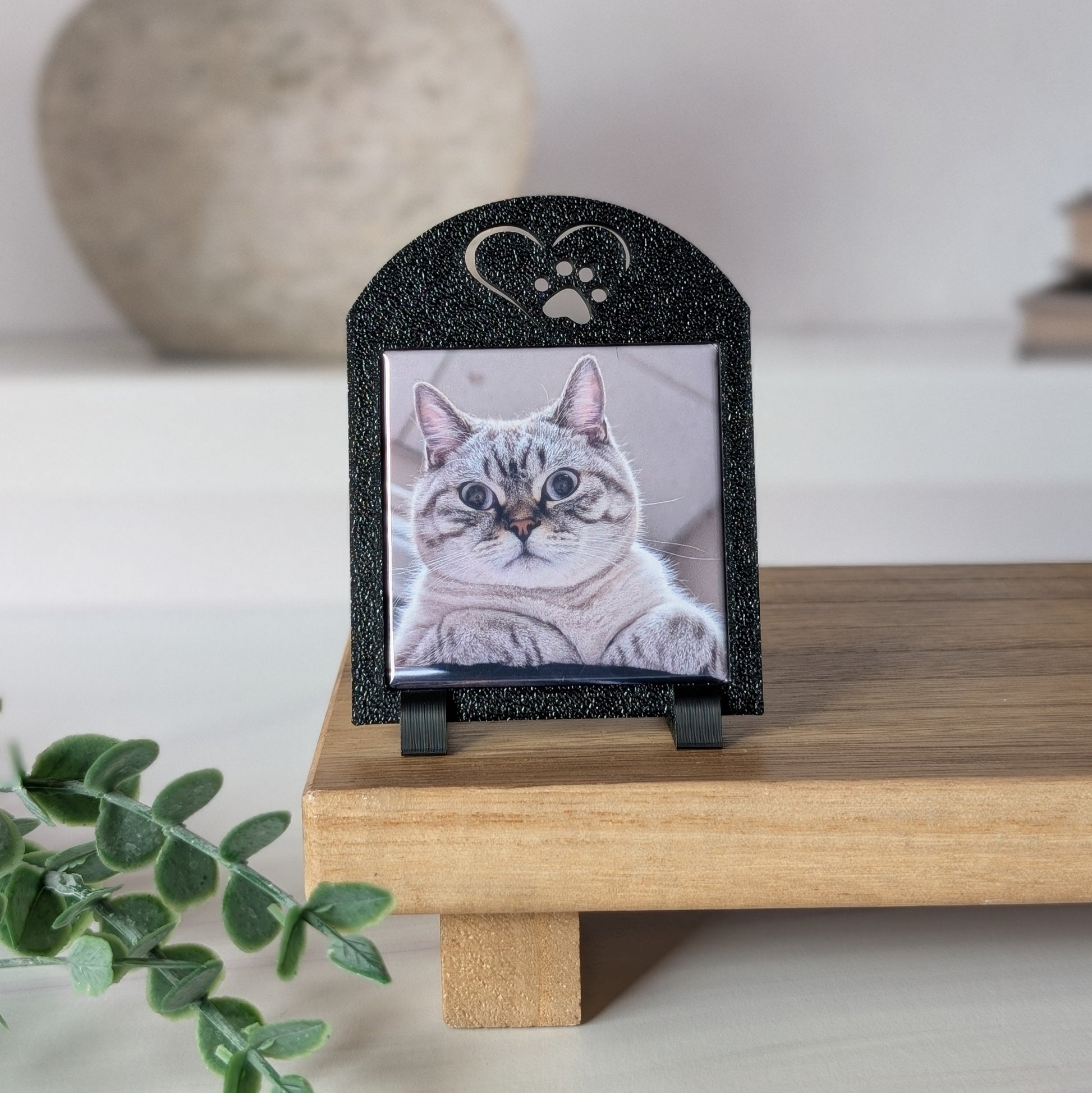 One black square photo magnet frame with an icon on the top of a heart outline around a paw.